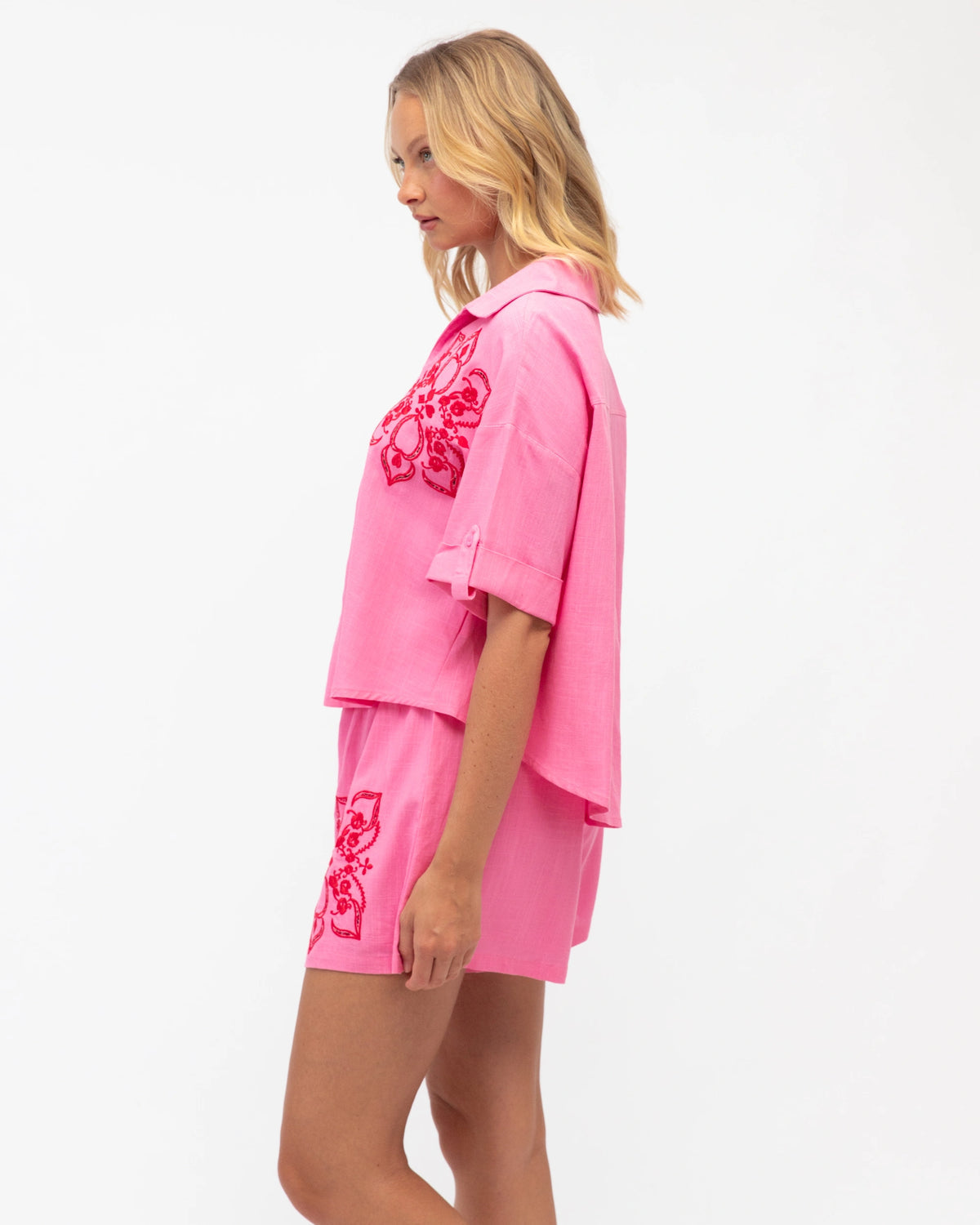 Woman wearing a pink outfit with floral embroidery on a white background