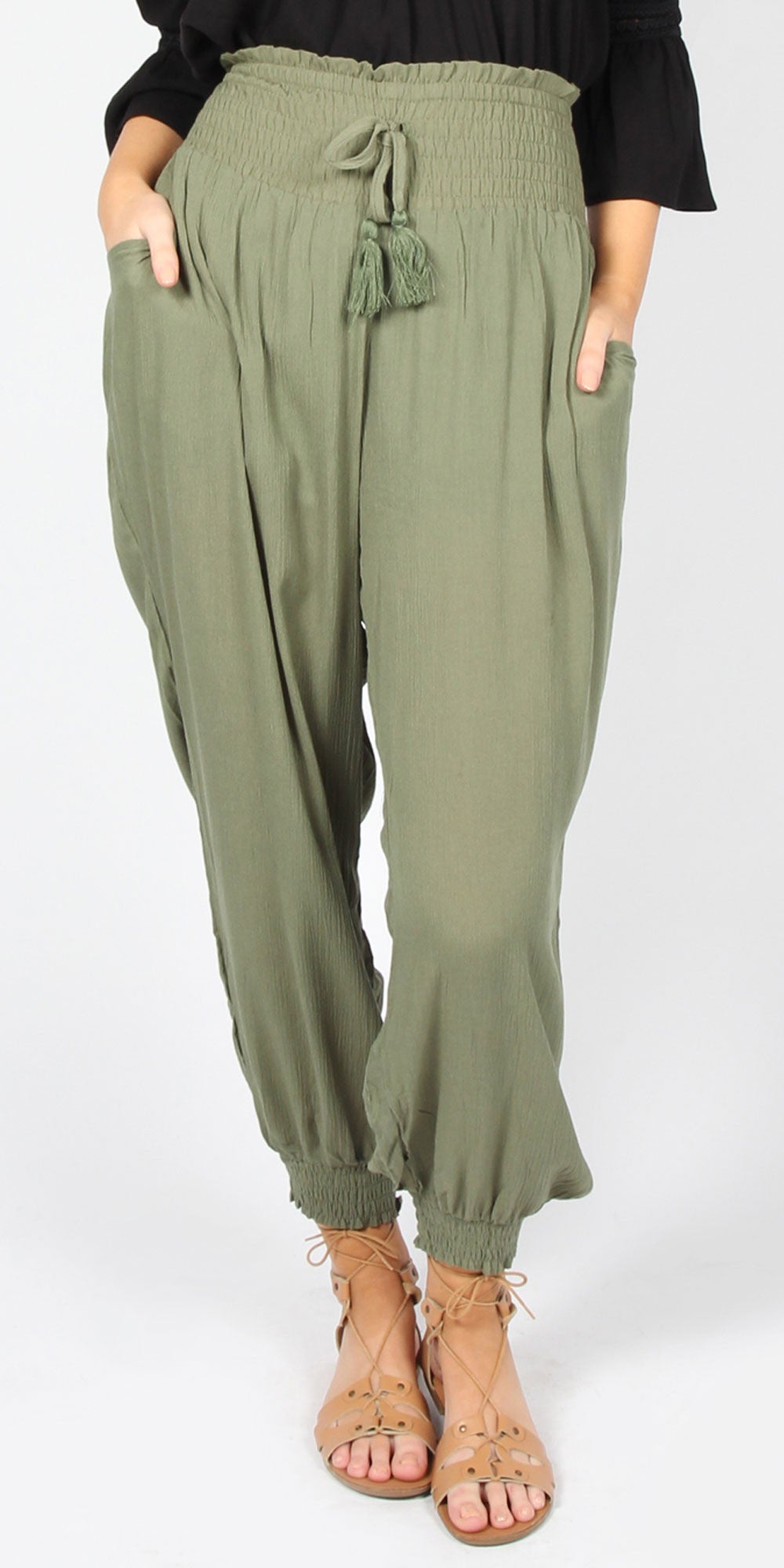 Green harem pants worn by a person on a white background