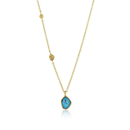 Gold necklace with a blue pendant on a white background