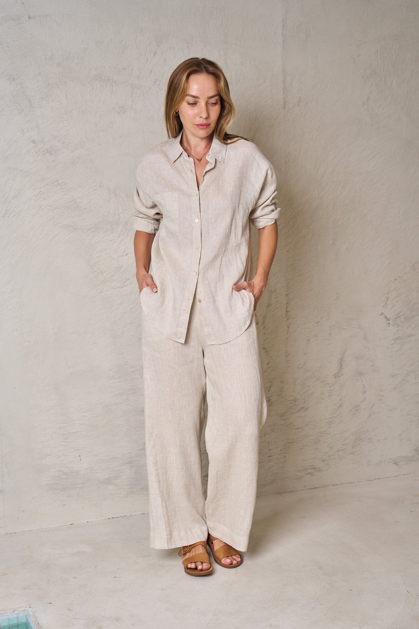 Woman wearing a beige linen outfit against a plain background