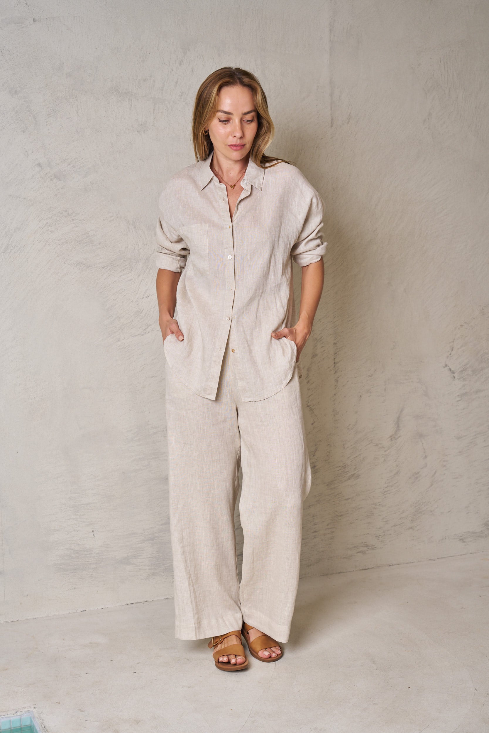 Woman wearing a beige linen outfit against a plain background